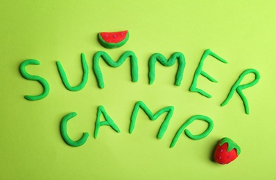 Words SUMMER CAMP made from modelling clay on color background, top view