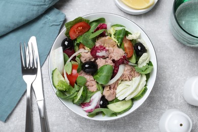 Bowl of delicious salad with canned tuna and vegetables served on light grey table, flat lay