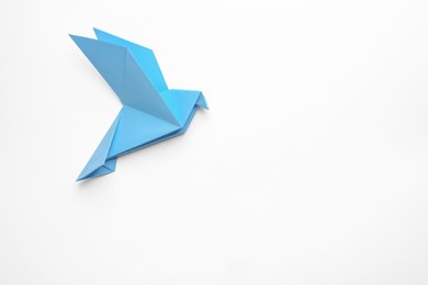 Beautiful light blue origami bird on white background, top view. Space for text
