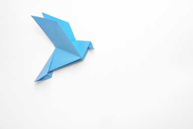 Photo of Beautiful light blue origami bird on white background, top view. Space for text