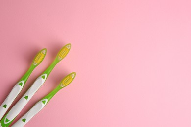 Photo of Toothbrushes on pink background, flat lay. Space for text