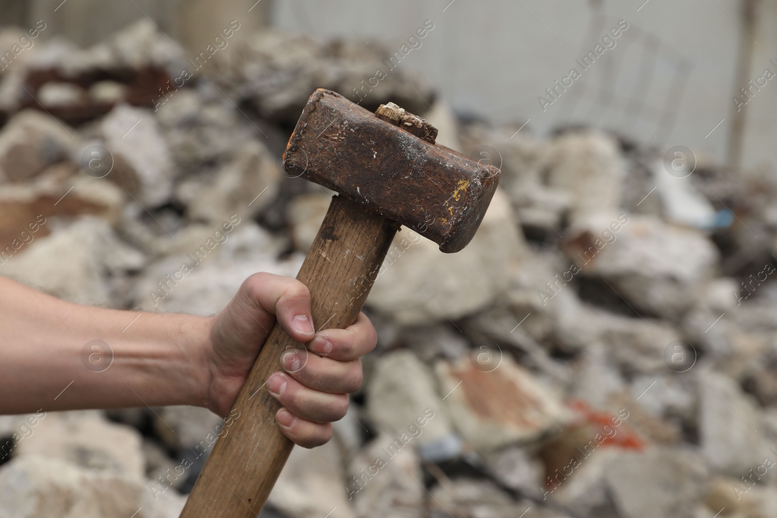 Photo of Man with sledgehammer near pile of stones outdoors, closeup. Space for text