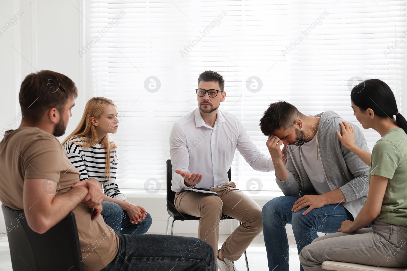 Photo of Psychotherapist working with group of drug addicted people at therapy session indoors