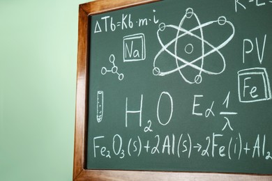 Blackboard with different chemical formulas written with chalk on light green wall