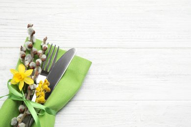 Photo of Top view of cutlery set with floral decor on white wooden table, space for text. Easter celebration