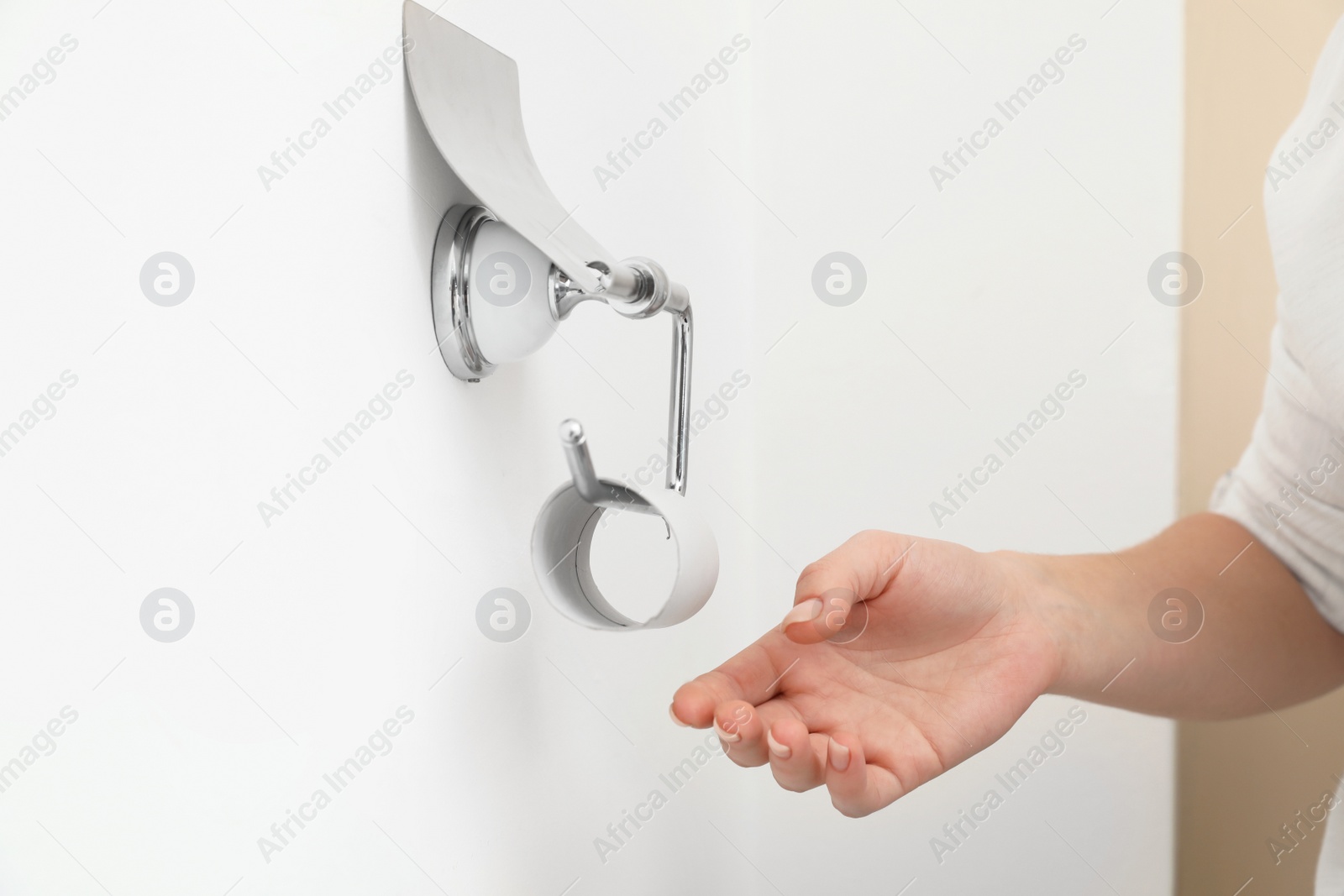 Photo of Woman reaching holder with empty toilet paper roll, closeup