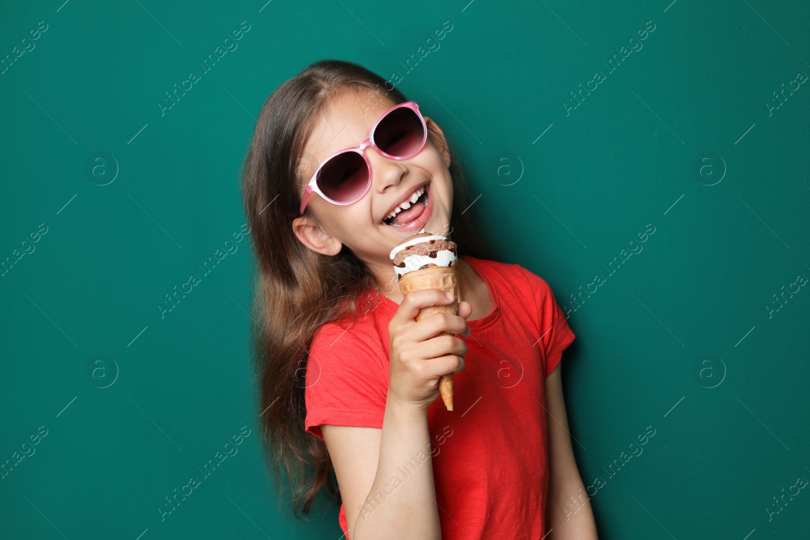 Photo of Adorable little girl with delicious ice cream against color background