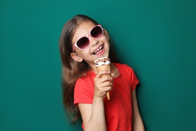 Photo of Adorable little girl with delicious ice cream against color background