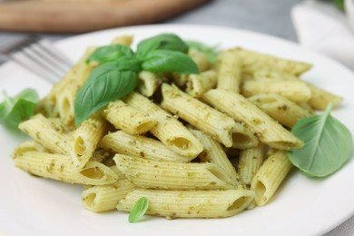 Photo of Delicious pasta with pesto sauce and basil on plate, closeup