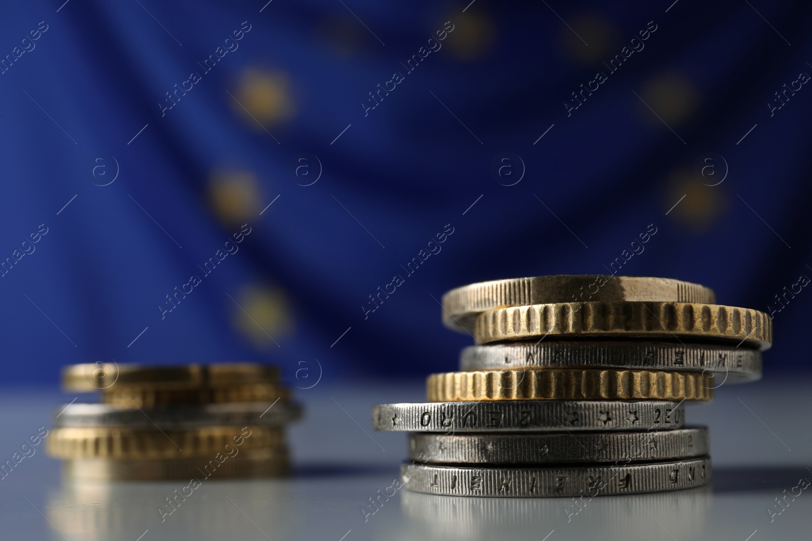 Photo of Many different coins on table against European Union flag, closeup. Space for text