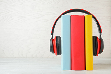 Books and modern headphones on white wooden table. Space for text