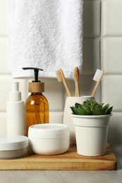 Photo of Different bath accessories and personal care products on gray table near white tiled wall