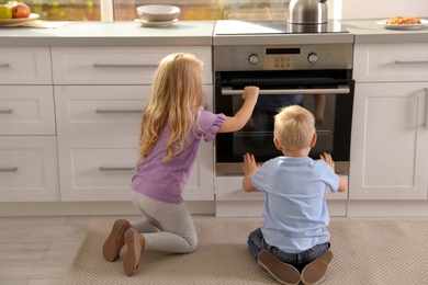 Little kids baking something in oven at home