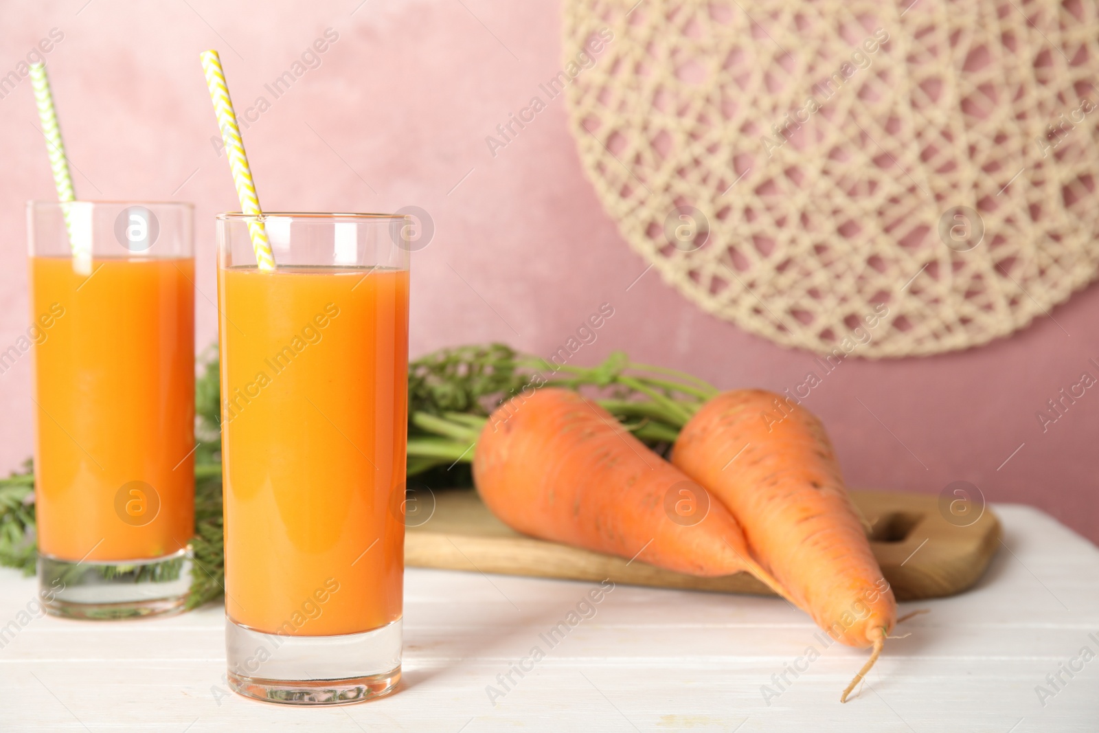 Photo of Freshly made carrot juice on white wooden table