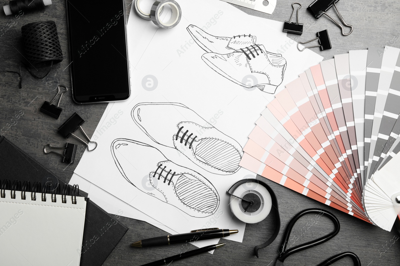 Photo of Flat lay composition with drawing of shoes on grey table. Designer's workplace