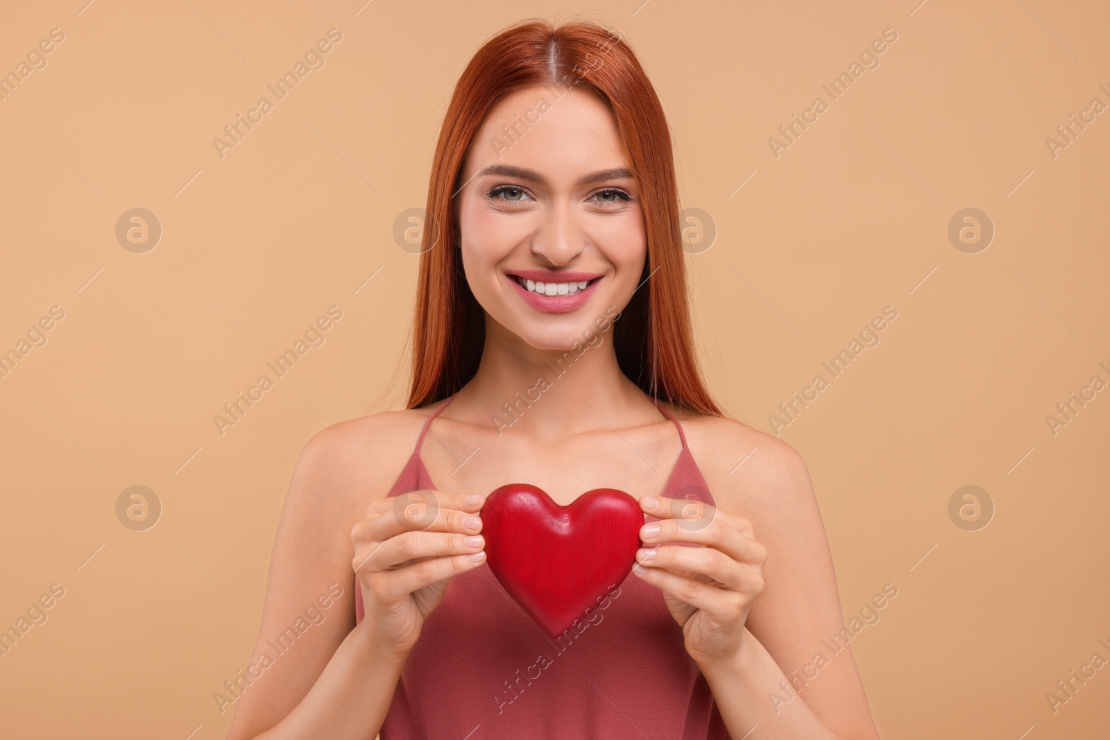 Photo of Beautiful happy woman with red heart on beige background