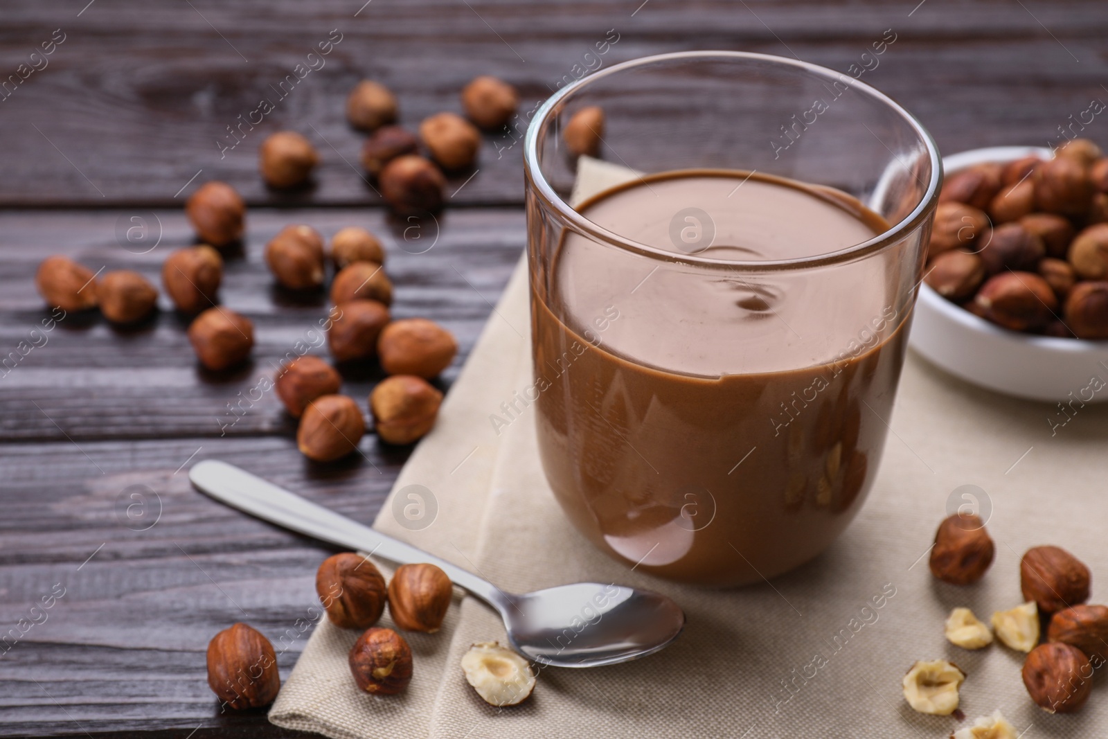 Photo of Glass with chocolate paste and nuts on wooden table. Space for text