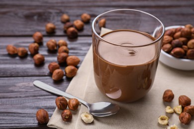 Glass with chocolate paste and nuts on wooden table. Space for text