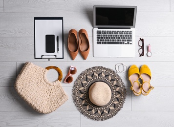 Photo of Flat lay composition with business supplies and beach accessories on white wooden floor. Concept of balance between work and life