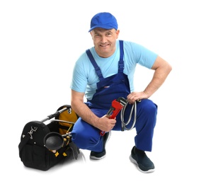 Photo of Mature plumber with pipe wrench and hose on white background