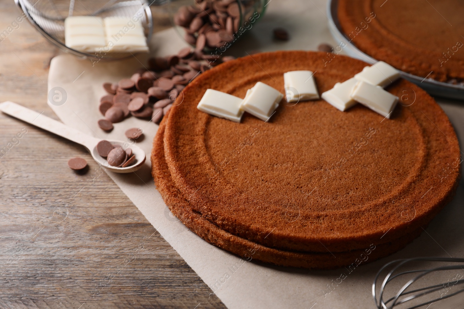 Photo of Delicious homemade sponge cake and different kinds of chocolate on wooden table, closeup