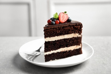 Photo of Plate with slice of chocolate sponge berry cake on grey table