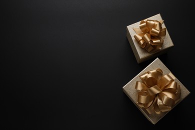 Golden gift boxes on black background, flat lay. Space for text