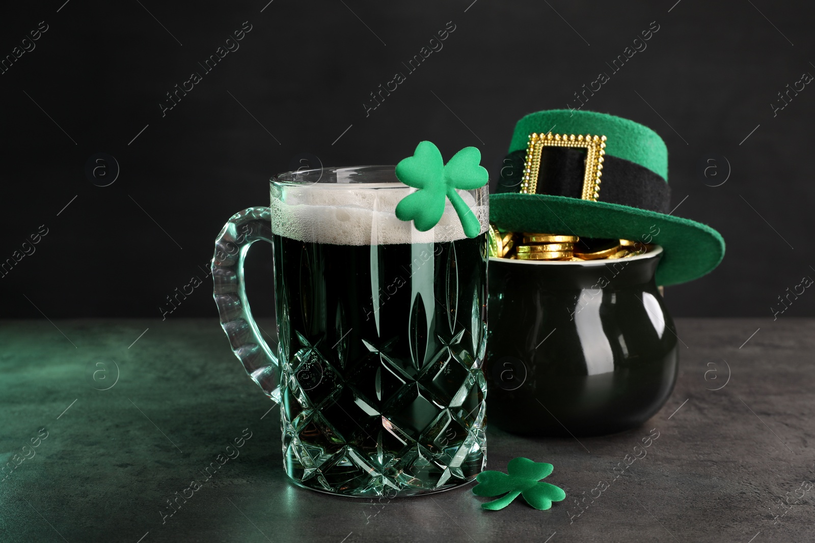 Photo of St. Patrick's day celebration. Green beer, leprechaun hat, pot of gold and decorative clover leaves on grey table