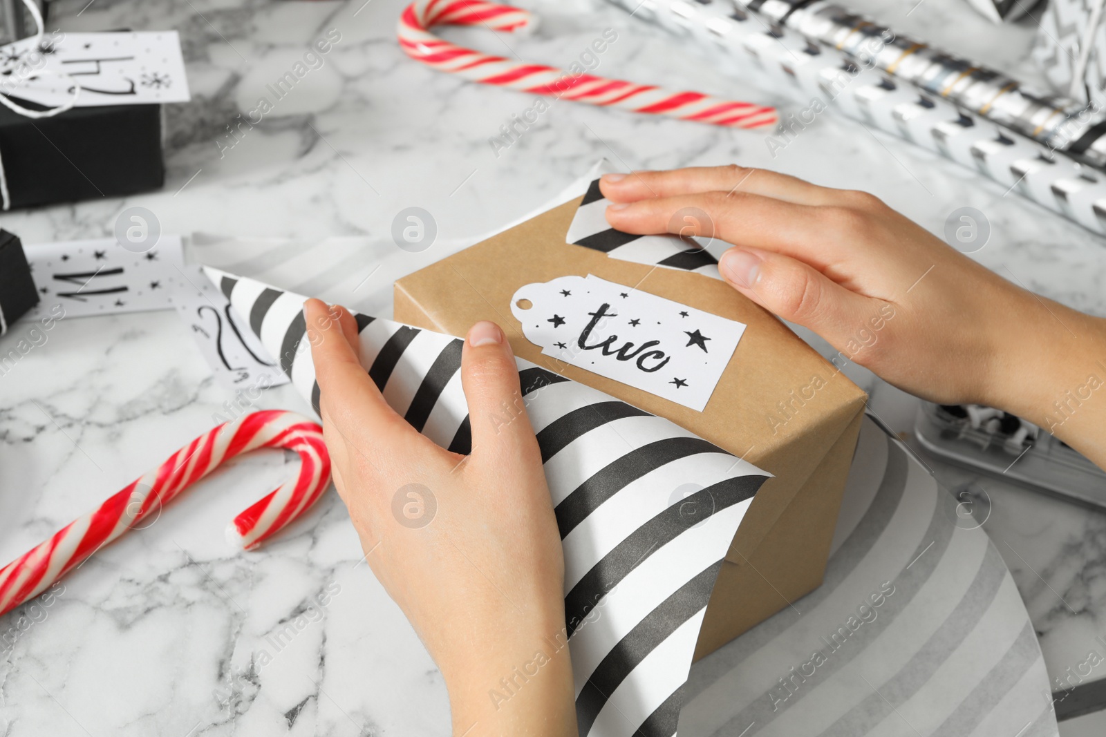 Photo of Woman making advent calendar at white marble table, closeup