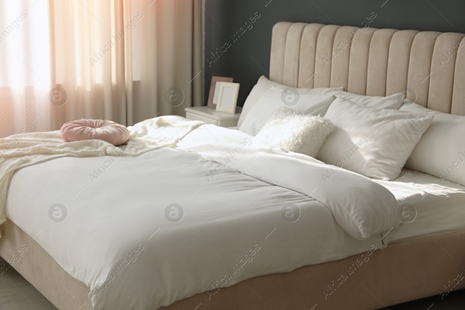 Photo of Comfortable bed with soft blanket near window indoors