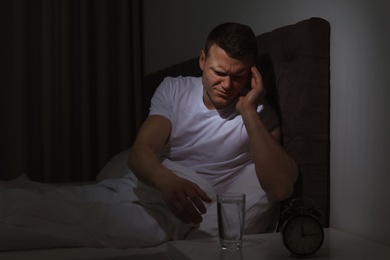 Photo of Young man with terrible headache want to take pill at night