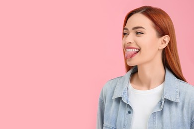 Photo of Happy woman showing her tongue on pink background. Space for text