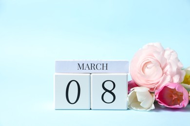 Photo of International Women's day - 8th of March. Wooden block calendar and beautiful flowers on light blue background. Space for text