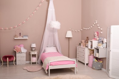 Photo of Cute child's room interior with toys and modern furniture