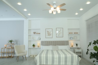 Photo of Comfortable furniture, ceiling fan, houseplants and accessories in stylish bedroom