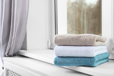 Photo of Folded clean towels on window sill. Space for text