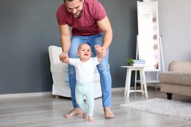 Baby taking first steps with father's help at home