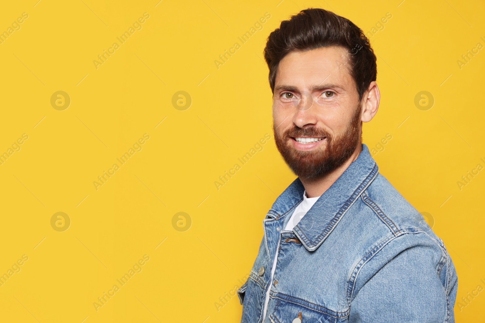 Photo of Portrait of smiling bearded man on orange background. Space for text