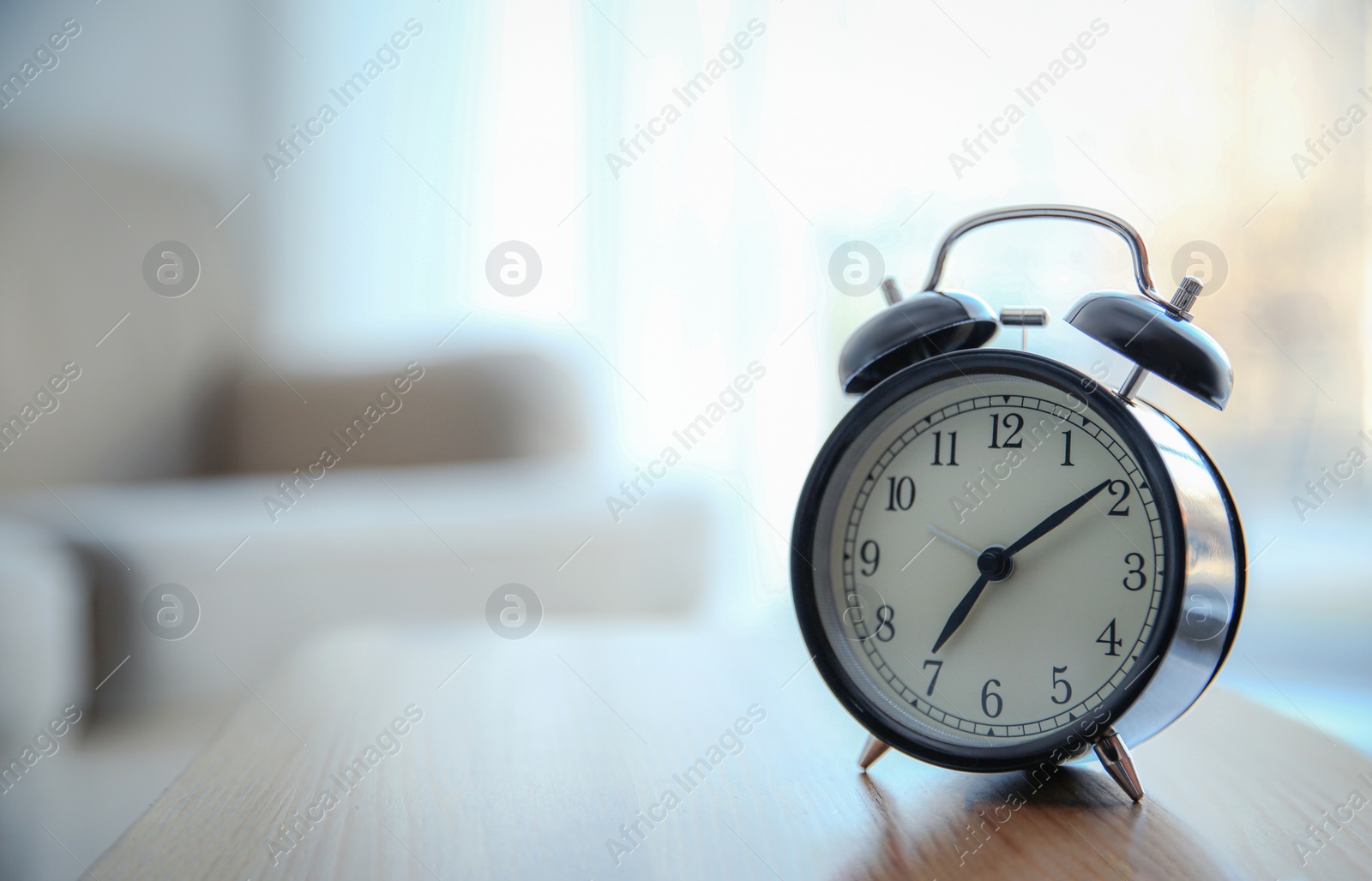 Photo of Alarm clock on wooden table at home. Morning time