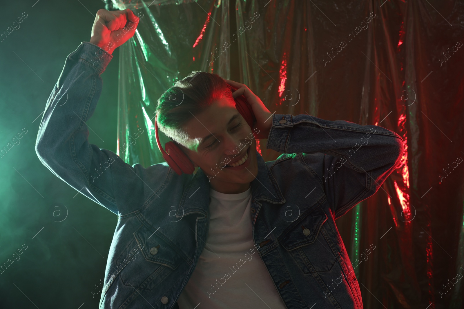 Photo of Young man with headphones dancing in neon lights