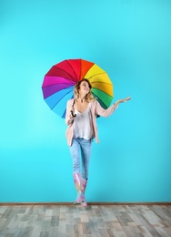 Woman with rainbow umbrella near color wall