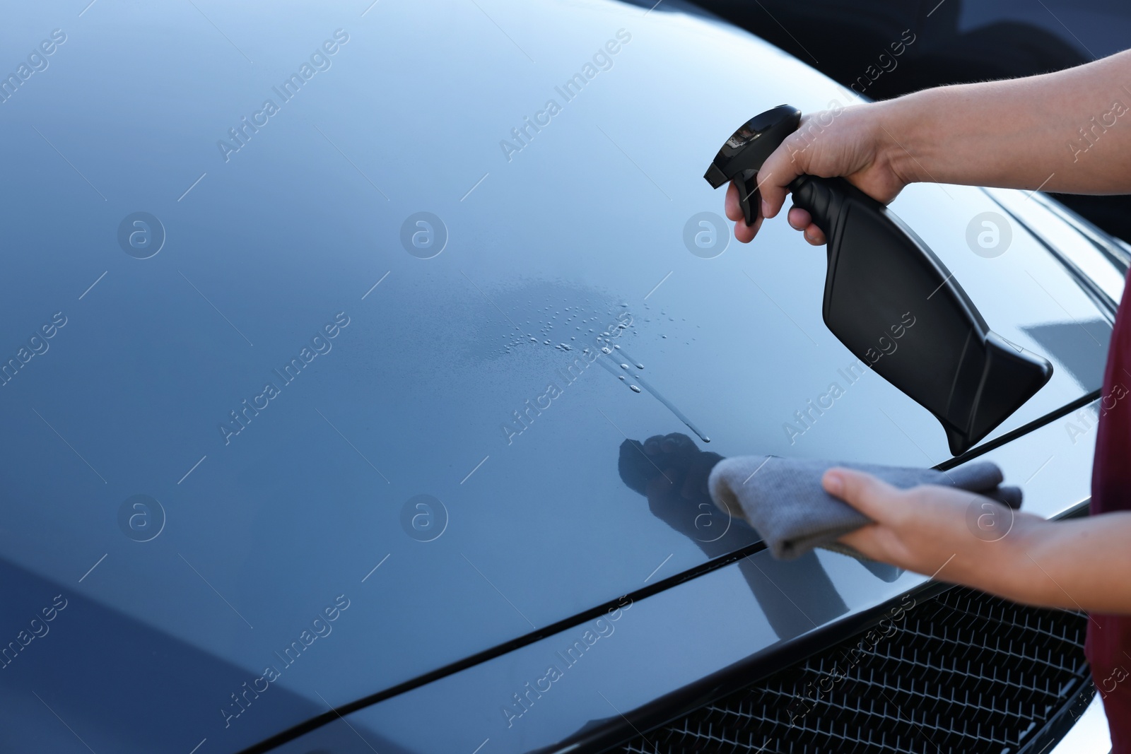 Photo of Man cleaning car hood outdoors, closeup view