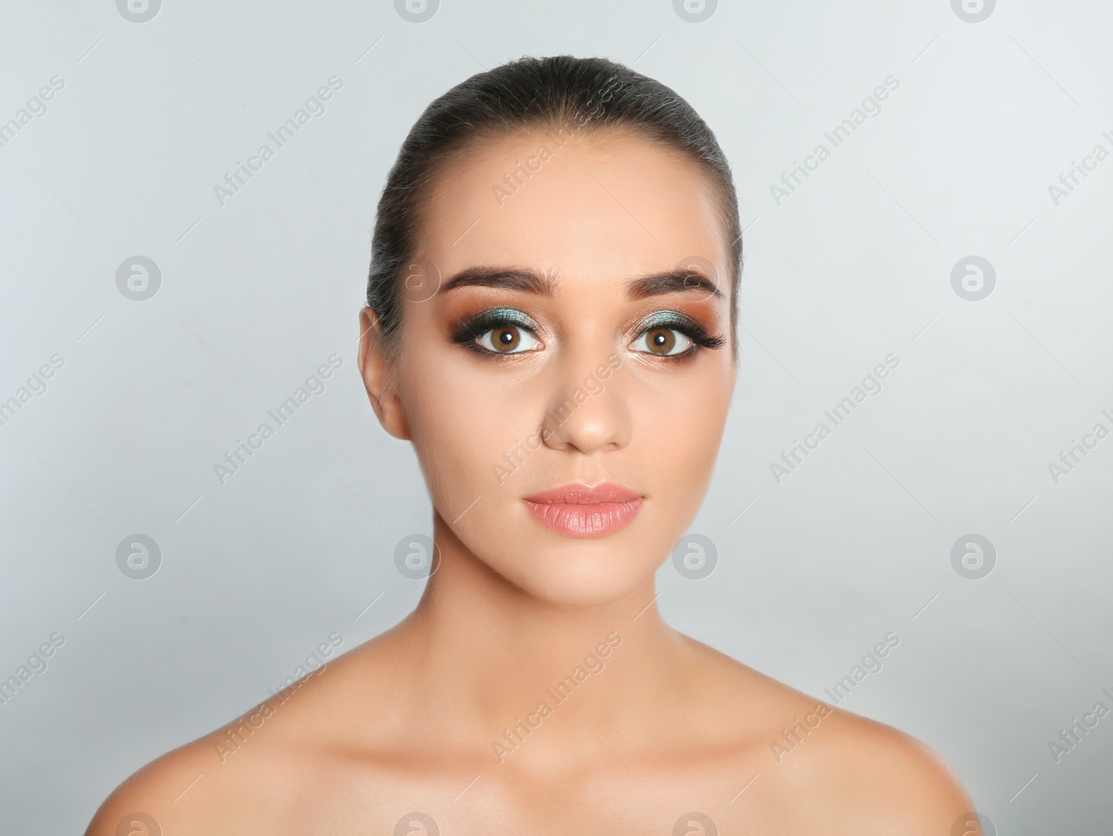 Photo of Portrait of young woman with eyelash extensions and beautiful makeup on light background