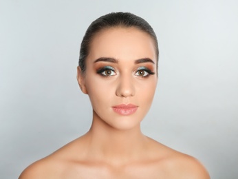 Photo of Portrait of young woman with eyelash extensions and beautiful makeup on light background