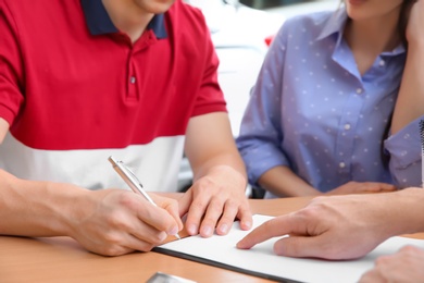 Photo of Young couple buying new car at dealership