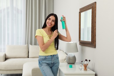 Photo of Woman applying dry shampoo onto her hair near mirror at home
