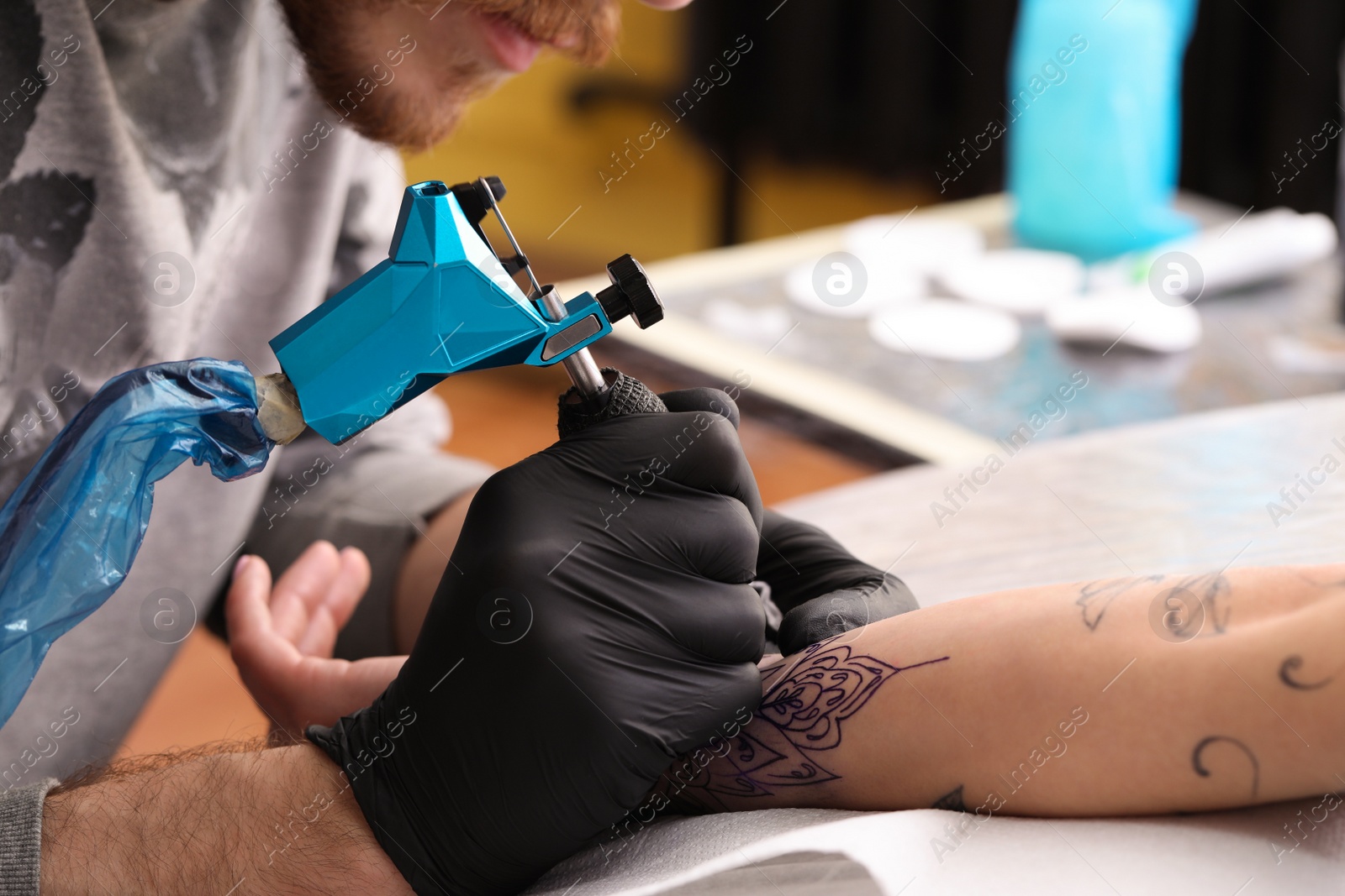 Photo of Professional artist making tattoo on hand in salon, closeup