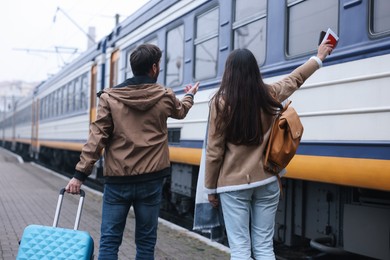Photo of Being late. Couple with suitcase at train station, back view