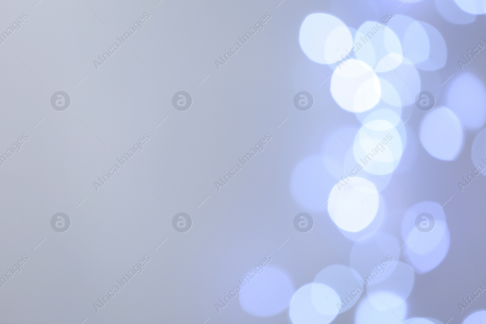 Photo of Blurred view of beautiful lights on light grey background, space for text