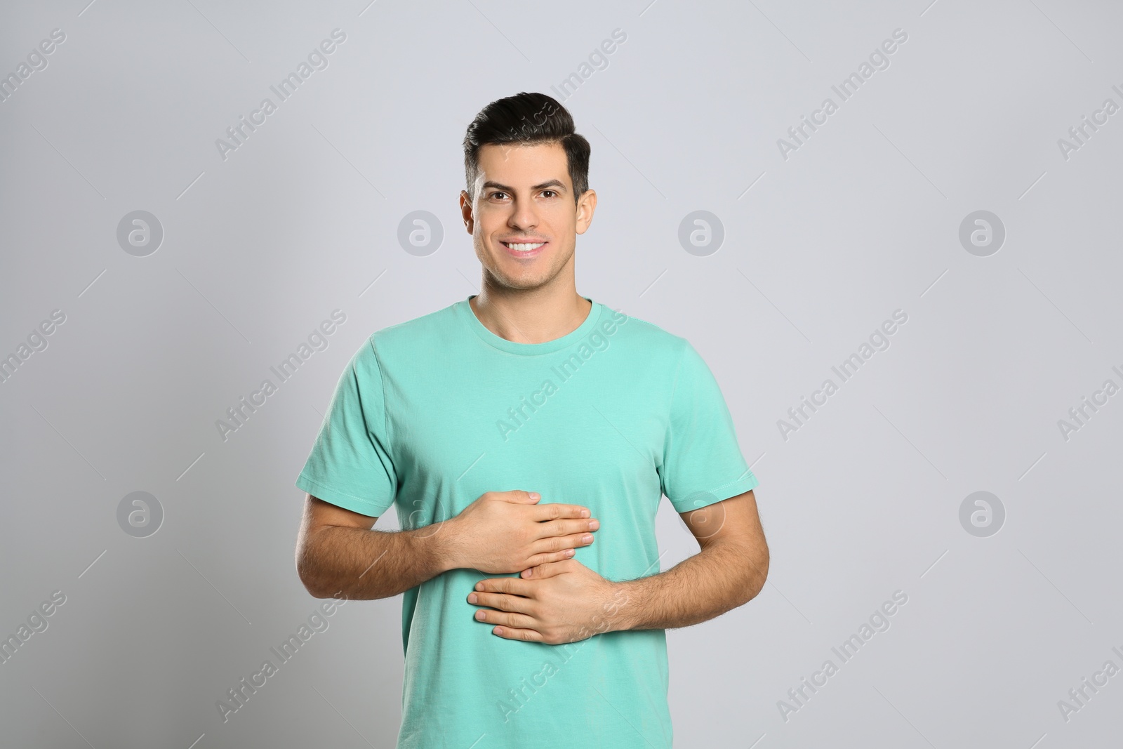 Photo of Happy healthy man touching his belly on light grey background